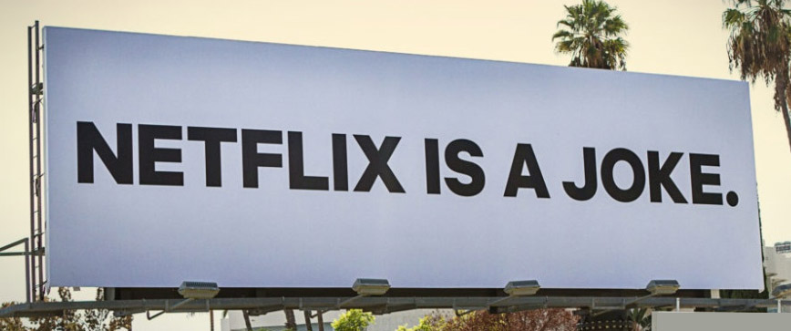 Billboard reads 'NETFLIX IS A JOKE.' on a pale blue sign with palm trees in the background.