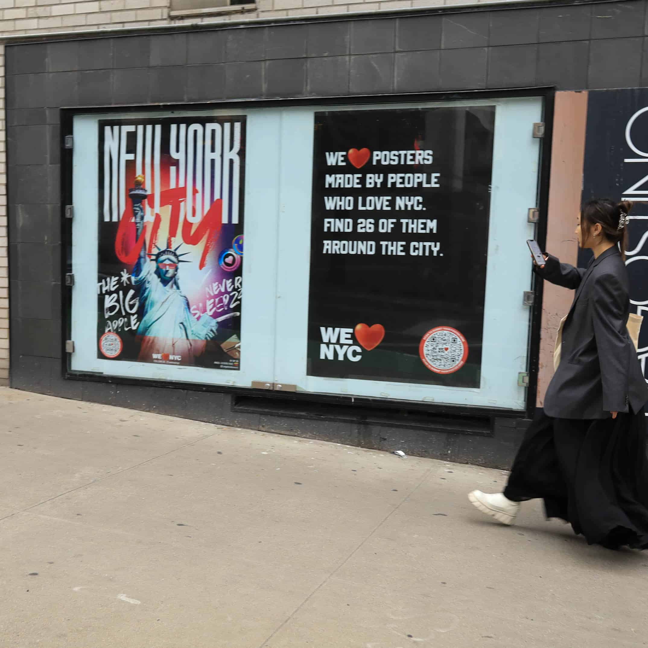 A person walks past two posters on a city sidewalk. One poster features New York City in bold with an image of a DJ. The other reads We ♥ Posters made by people who love NYC. Find 26 of them around the city.