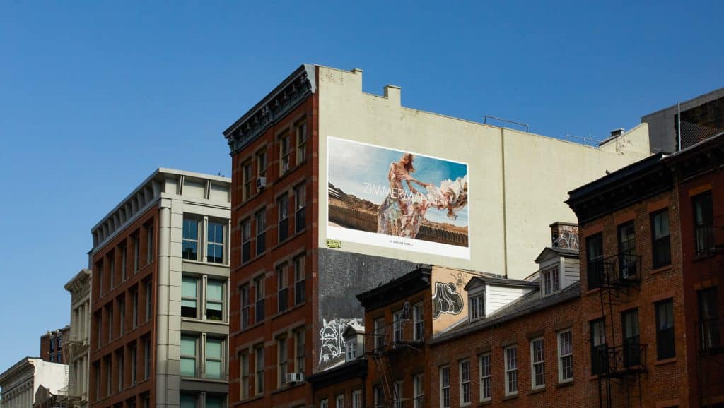 A large-scale mural advertisement for Zimmermann displayed on the side of a building in an urban environment under a clear blue sky.