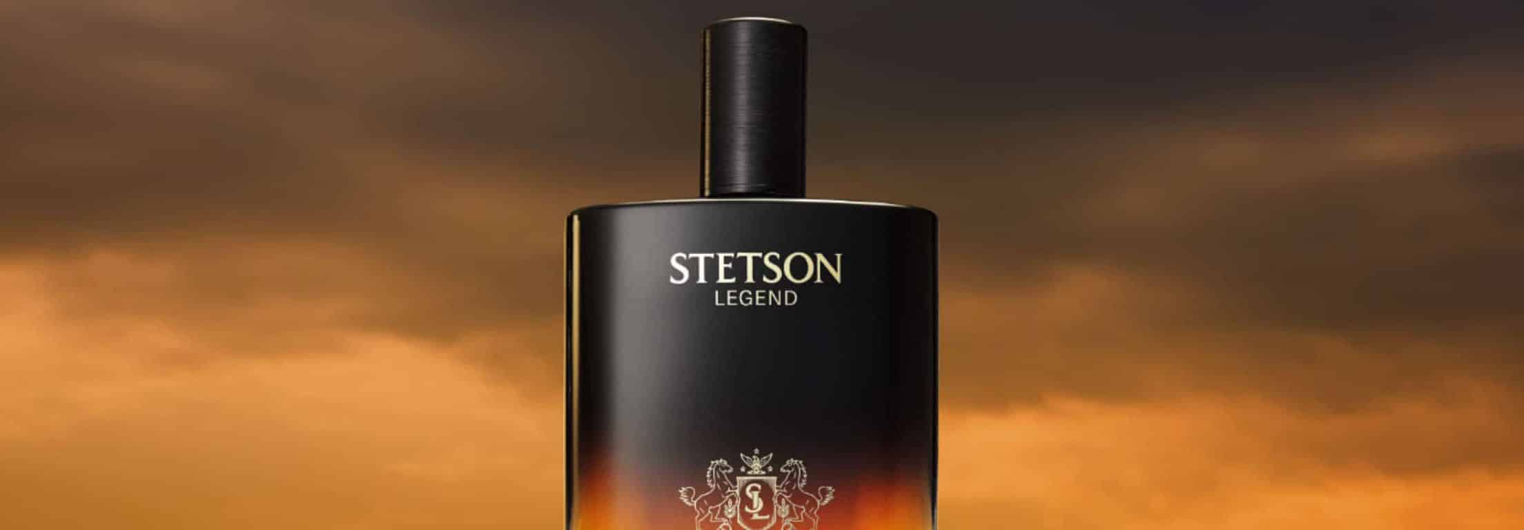 A black bottle of Stetson Legend cologne with a gold logo and text, set against a dramatic orange and brown sky background.