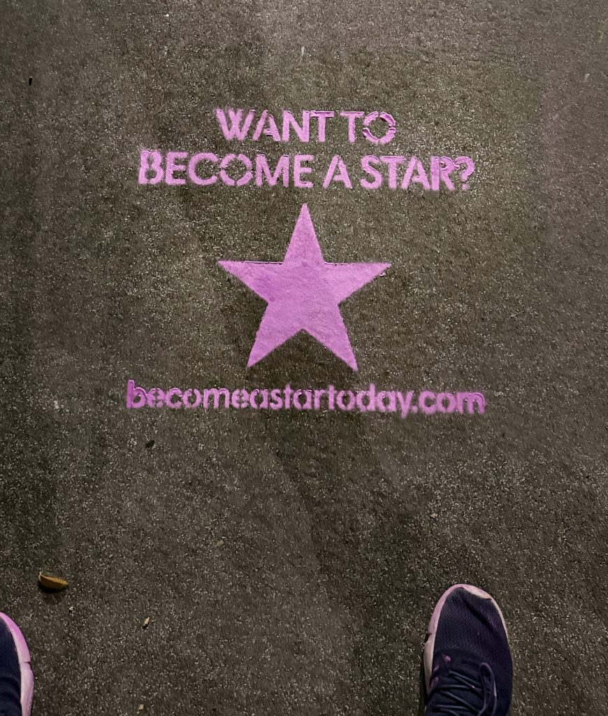 Pink chalk sidewalk stencil guerilla advertising campaign on a city street