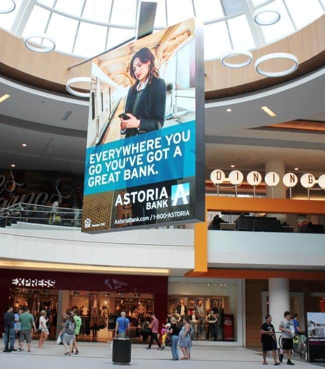 Large sky banner ad for Astoria Bank hanging from a shopping mall ceiling