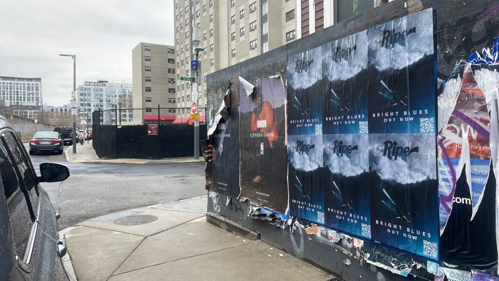Urban street corner with a wall covered in torn posters; blue ads for Bright Blues, and a man peeking from behind them.