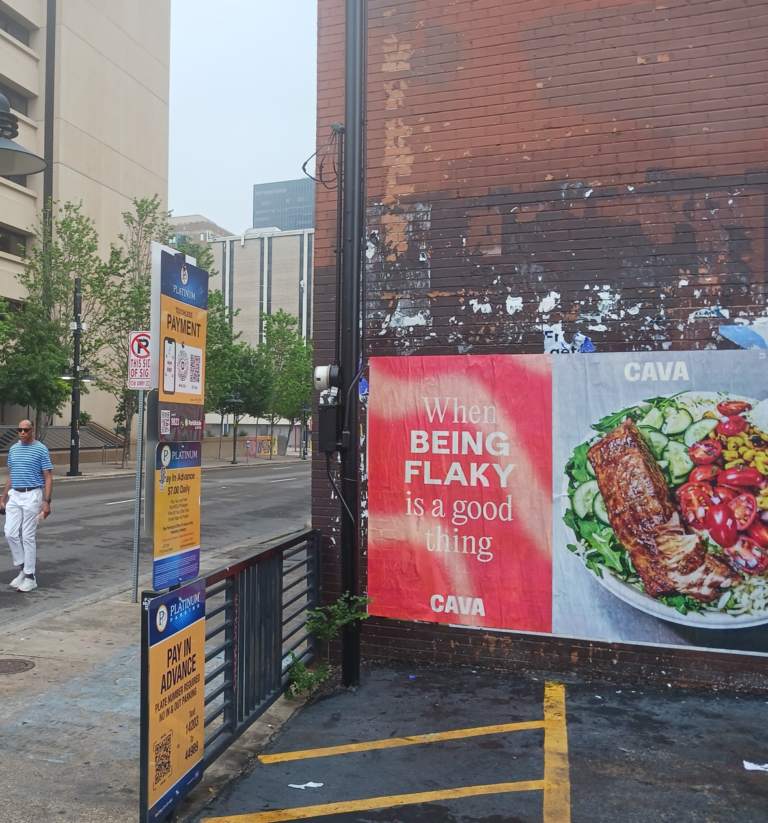 CAVA "When Being Flaky Is a Good Thing" Wild Posting® campaign in Dallas — two-panel wheat-pasted wall installation on a downtown brick corner featuring the brand's grilled fish bowl, installed by DASH TWO.