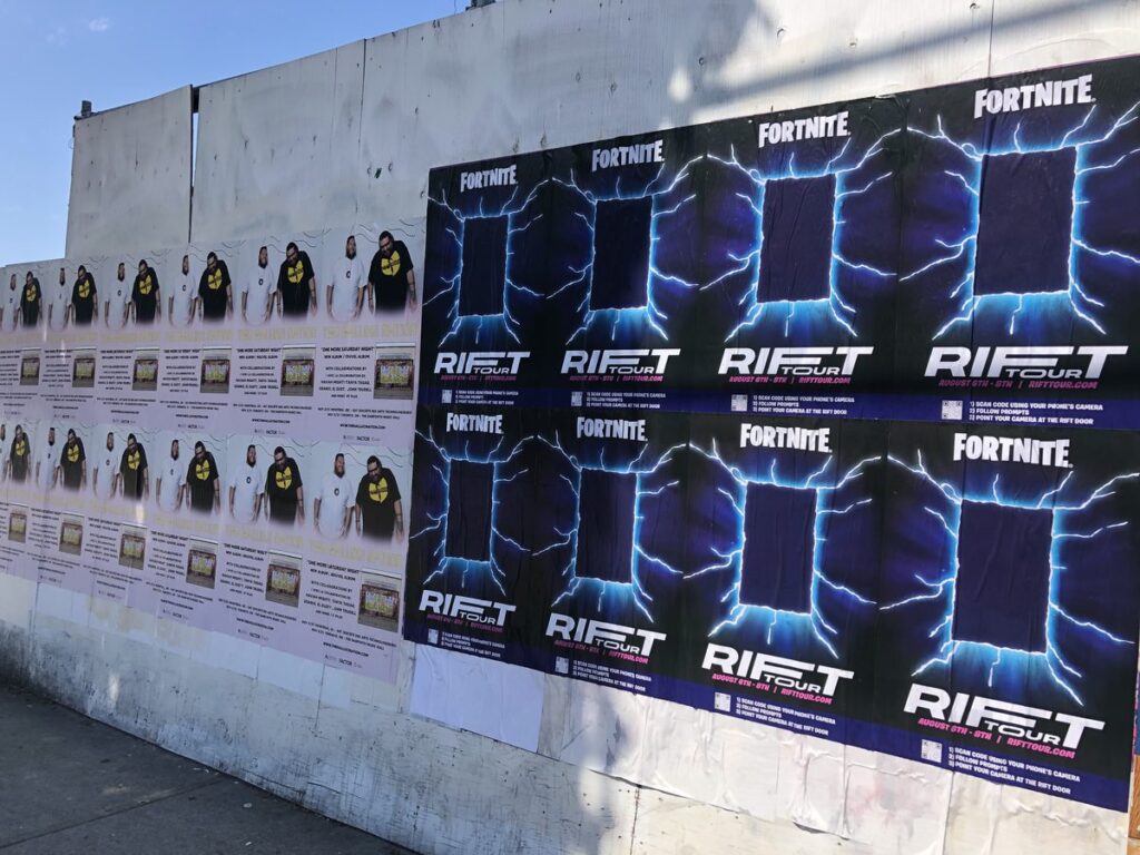 Wall covered with Fortnite Riot Tour posters featuring blue lightning and dark panels on a fence-like backdrop.