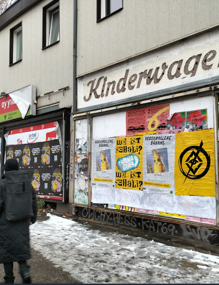 Multi-brand wheat pasting wall in Berlin featuring Fortnite Verschollene Banane (Wo ist Schali?) and Neucom grocery delivery campaigns — Wild Posting® installs by DASH TWO on a Berlin street-level barricade