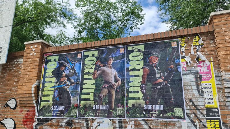 Three large Fortnite posters pinned to a weathered brick wall, each showing a different character and the date '9 DE JUNIO'.