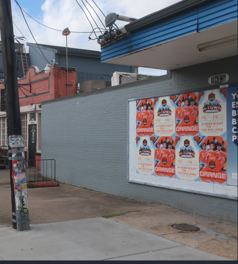 Wild Posting® campaign in Houston for Houston Dynamo FC's "H-Town Celebration" homestand — "Forever Orange Forever Houston" and "H-Town Night featuring Mike Jones" posters wheat-pasted on a brick wall in EaDo near Shell Energy Stadium