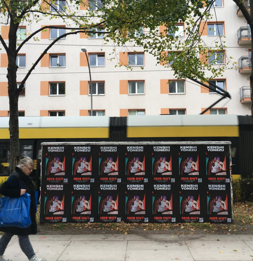 Kenshi Yonezu IRIS OUT wheat pasting takeover in Berlin Friedrichshain — 14-poster barricade for the Chainsaw Man: Reze Arc theme song, installed along a tram corridor as part of a Wild Posting® campaign by DASH TWO
