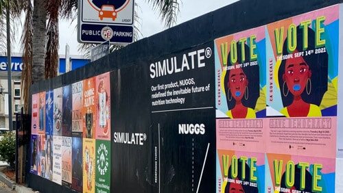 Wild posting wall on Santa Monica Boulevard featuring "Vote Tuesday Sept 14, 2021" civic engagement posters alongside SIMULATE brand advertising.