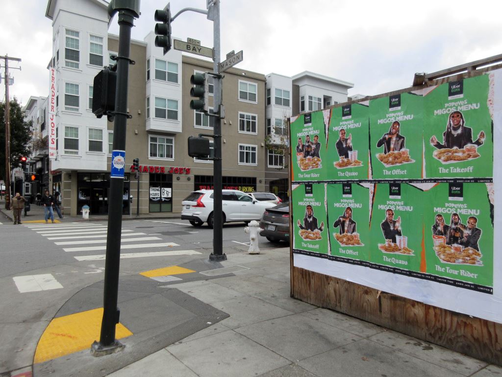 Uber Eats × Popeyes "Migos Menu" Wild Posting® at Bay & Mason, San Francisco — eight wheat-pasted posters across from Trader Joe's