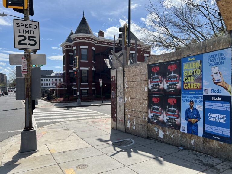 Wild Posting wheat pasting campaign on N Capitol Street NW, Washington DC, featuring Roda auto service and Rayo concert posters on a plywood barricade with a brick Victorian rowhouse in the background.